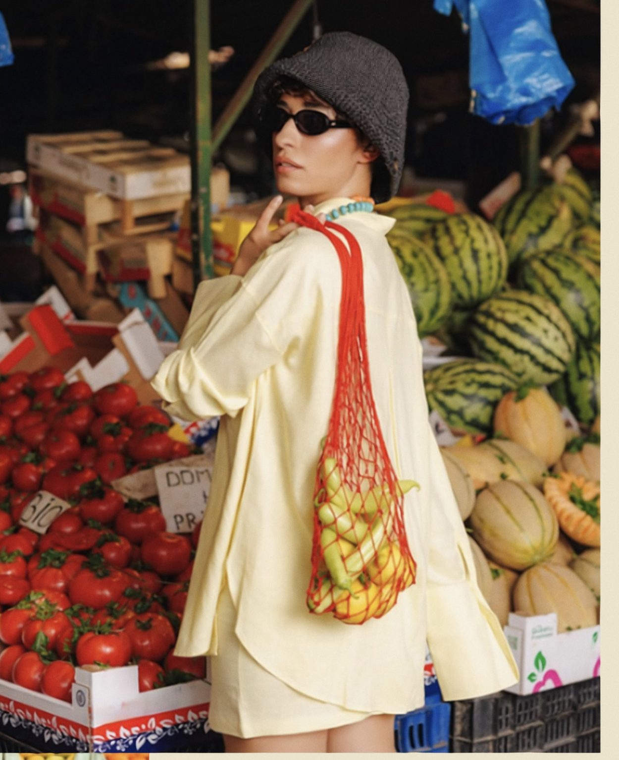 Mujer en una plaza de mercado de Bogotá con una bolsa de malla llena de fruta